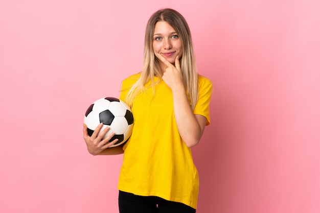 Joven futbolista mujer aislada en la pared rosa riendo