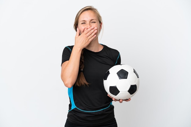 Joven futbolista mujer aislada sobre fondo blanco feliz y sonriente cubriendo la boca con la mano