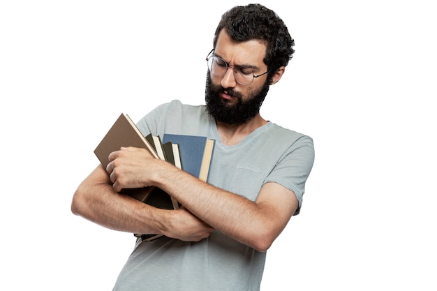 Foto un joven con gafas y barba con libros en sus manos con emoción en su rostro. educación y entrenamiento. aislado.