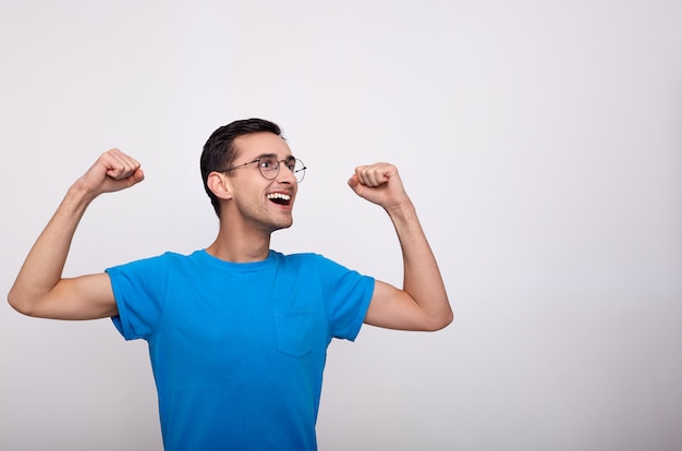 Un joven con gafas y una camiseta azul celebra la victoria.