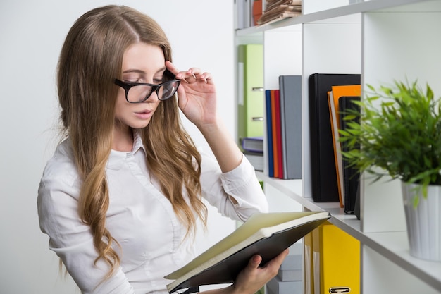 La joven con gafas está leyendo un libro