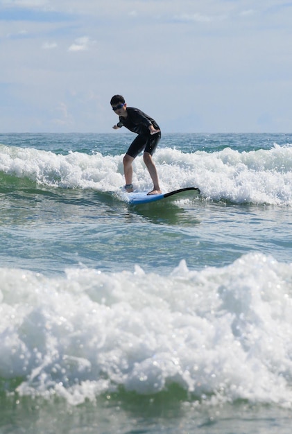 Foto un joven con gafas de natación se para estable en una tabla blanda mientras practica surf en la clase de principiantes