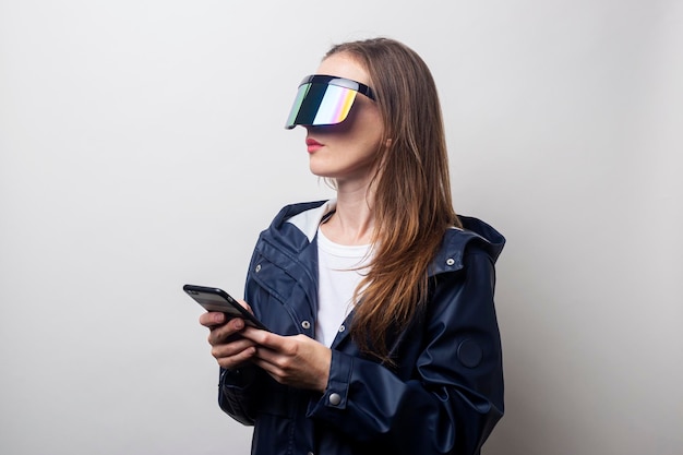 Una joven con gafas de realidad virtual sostiene un teléfono con un fondo claro