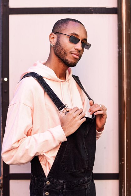 Foto joven con gafas de sol mientras está de pie contra una puerta cerrada