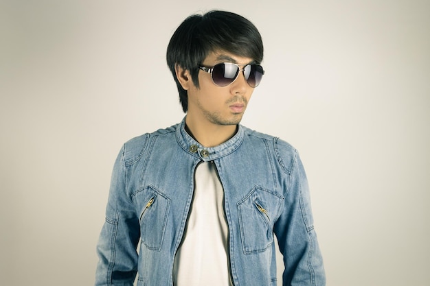 Joven con gafas de sol de pie contra un fondo blanco
