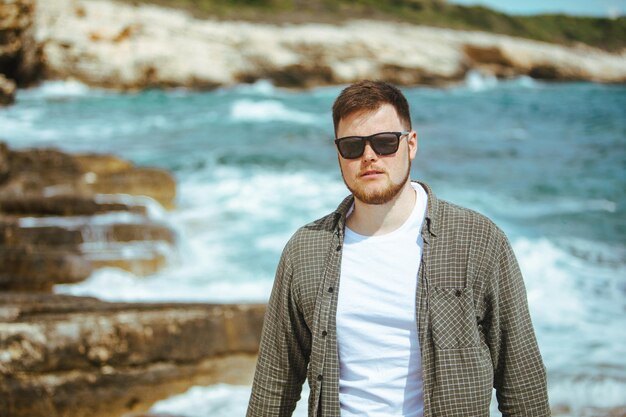 Joven con gafas de sol con retrato de barba en las vacaciones de verano junto al mar