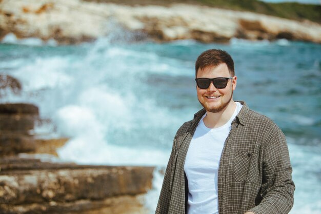 Joven con gafas de sol con retrato de barba en las vacaciones de verano junto al mar