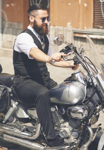 Joven con gafas de sol y sentado en una moto