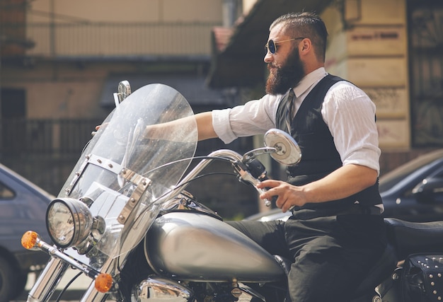 Joven con gafas de sol y sentado en una moto