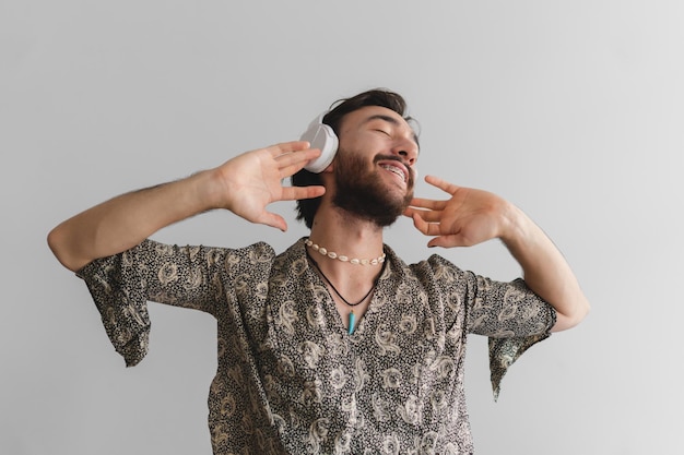 Joven gay latino queer bailando mientras escucha música a través de auriculares inalámbricos