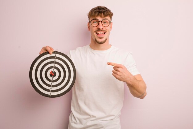 Joven genial que parece emocionado y sorprendido señalando el concepto de objetivo de dardo lateral