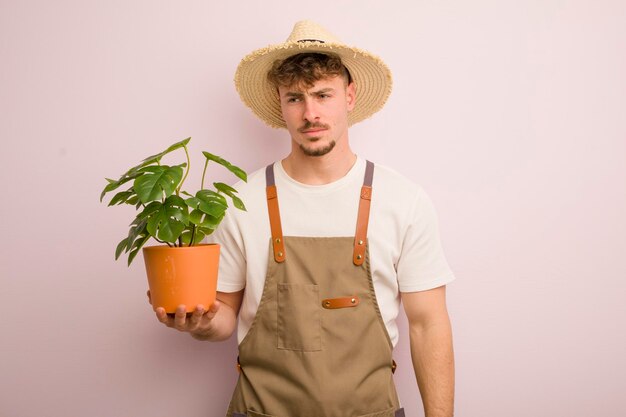 Joven genial que se siente triste, molesto o enojado y mira hacia el lado del jardinero y la planta