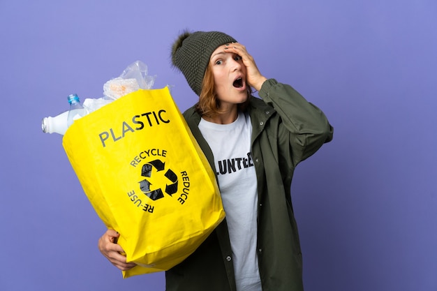 Foto joven georgiana sosteniendo una bolsa llena de botellas de plástico para reciclar haciendo un gesto de sorpresa mientras mira hacia un lado