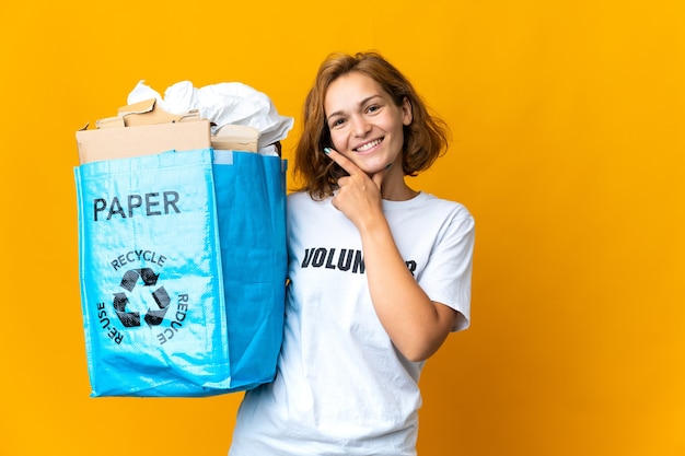 Joven georgiana sosteniendo una bolsa de reciclaje llena de papel para reciclar feliz y sonriente