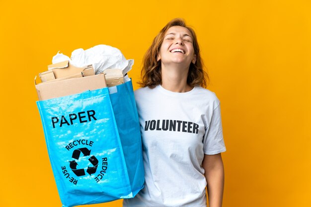 Joven georgiana sosteniendo una bolsa de reciclaje llena de papel para reciclar riendo