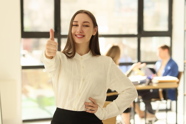 Joven gerente sonriendo y mostrando los pulgares hacia arriba en la oficina buena retroalimentación y concepto de