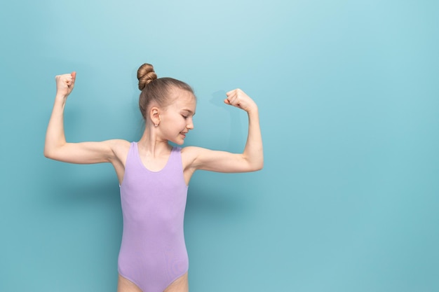 Una joven gimnasta estirando sus músculos imagina que tiene un brazo poderoso con grandes bíceps