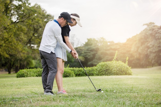 Joven golfista asiática haciendo práctica con su entrenador de golf profesional en el club de golf