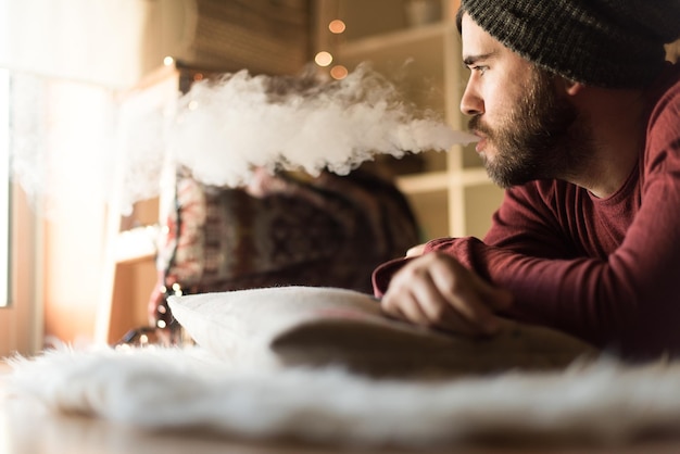 Joven con un gorro de lana usando un vaper