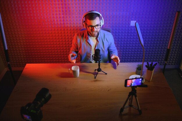 Joven grabando o transmitiendo podcast usando un micrófono en su pequeño estudio de transmisión Creador de contenido