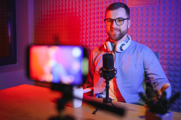 Joven grabando o transmitiendo podcast usando un micrófono en su pequeño estudio de transmisión Creador de contenido