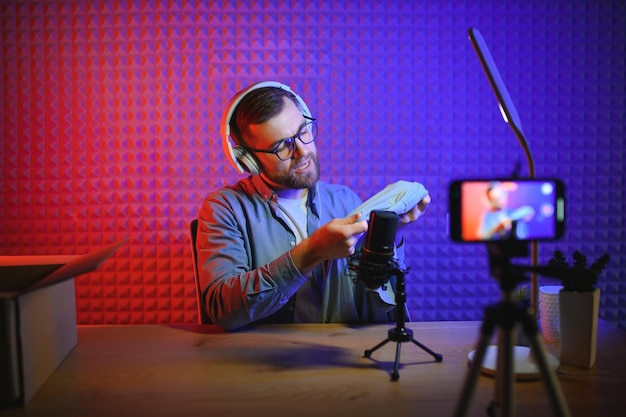 Joven grabando o transmitiendo podcast usando un micrófono en su pequeño estudio de transmisión Creador de contenido