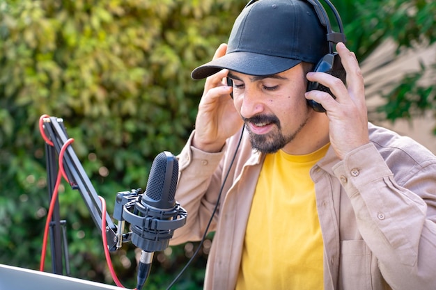 Joven grabando podcast de radio hablando durante una sesión de transmisión en vivo al aire libre