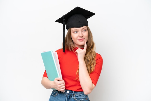 Joven graduada universitaria aislada de fondo blanco pensando en una idea mientras mira hacia arriba