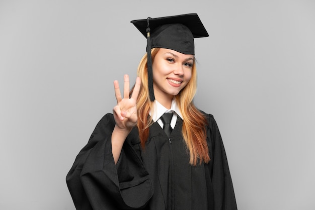 Joven graduada universitaria sobre antecedentes aislados feliz y contando tres con los dedos