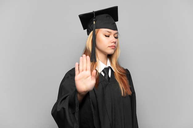 Joven graduada universitaria sobre antecedentes aislados haciendo gesto de parada y decepcionado