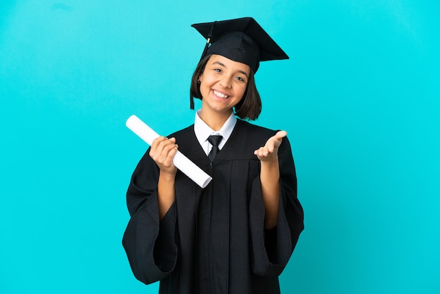 Joven graduada universitaria sobre fondo azul aislado un apretón de manos para cerrar un buen trato