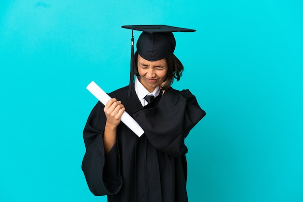 Joven graduada universitaria sobre fondo azul aislado con dolor de cuello