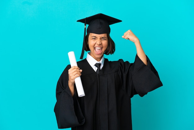 Joven graduada universitaria sobre fondo azul aislado haciendo un gesto fuerte