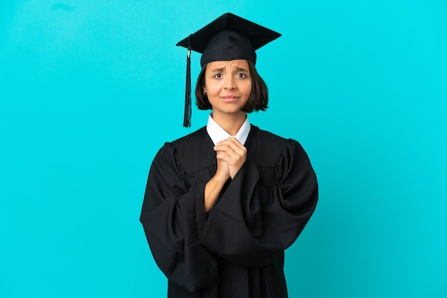 Joven graduada universitaria sobre fondo azul aislado riendo