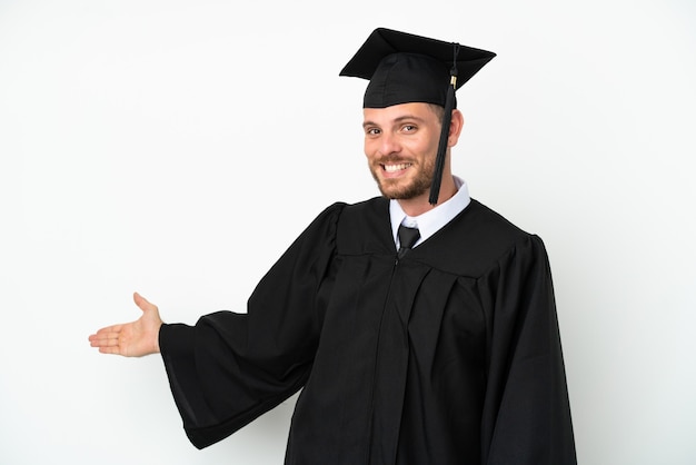 Joven graduado brasileño universitario aislado sobre fondo blanco extendiendo las manos hacia el lado para invitar a venir