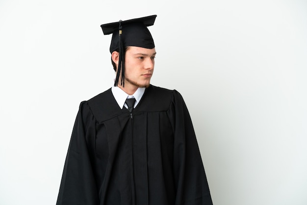 Joven graduado universitario ruso aislado sobre fondo blanco mirando hacia el lado