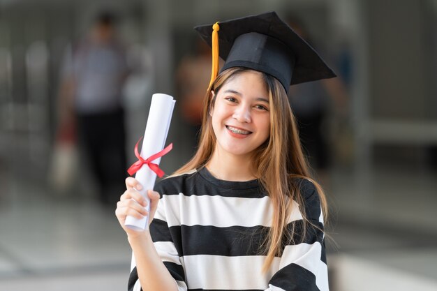 Un joven graduado universitario tiene un certificado de grado.