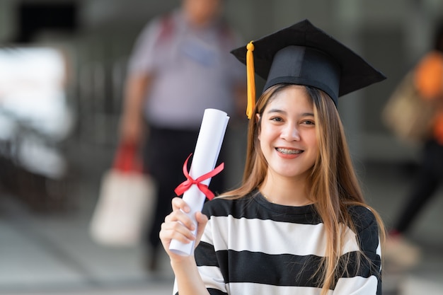 Un joven graduado universitario tiene un certificado de grado.