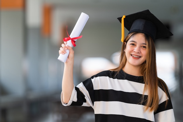 Un joven graduado universitario tiene un certificado de grado.