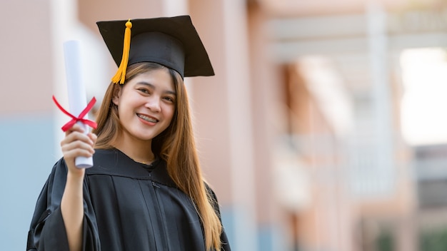 Un joven graduado universitario tiene un certificado de grado.