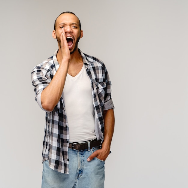 Joven gritando contra una pared gris