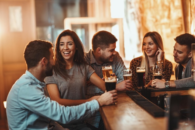 Un joven grupo de amigos bebe cerveza, habla y se divierte en un café.