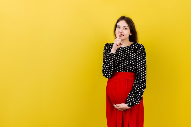 Joven guapa morena embarazada esperando un bebé sobre un fondo de color aislado pidiendo silencio con el dedo en los labios Silencio de maternidad y concepto secreto