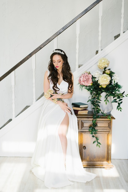 Una joven y guapa novia morena, vestida con un largo vestido de novia blanco