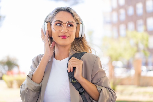 Joven guapa rubia uruguaya al aire libre escuchando música