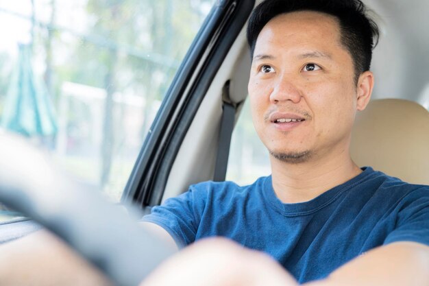 Joven guapo asiático conduciendo coche para viajar