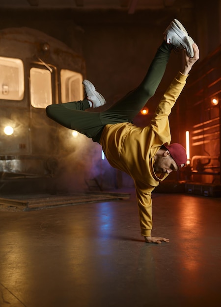 Un joven guapo bailando movimientos de hip hop bailando break sobre el fondo de un estudio urbano