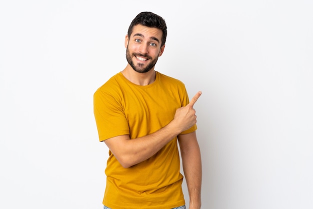 Joven guapo con barba aislado en blanco apuntando hacia el lado para presentar un producto