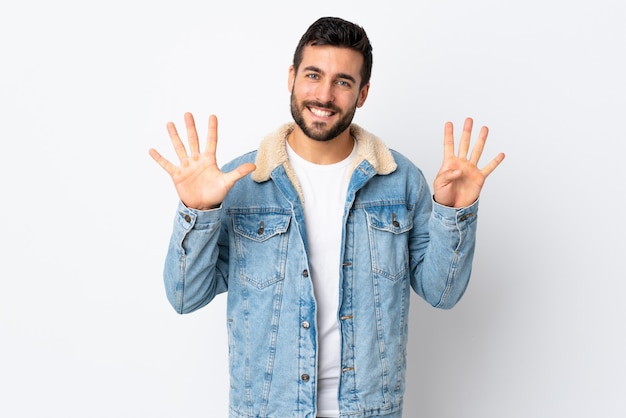 Joven guapo con barba aislado en la pared blanca contando nueve con los dedos