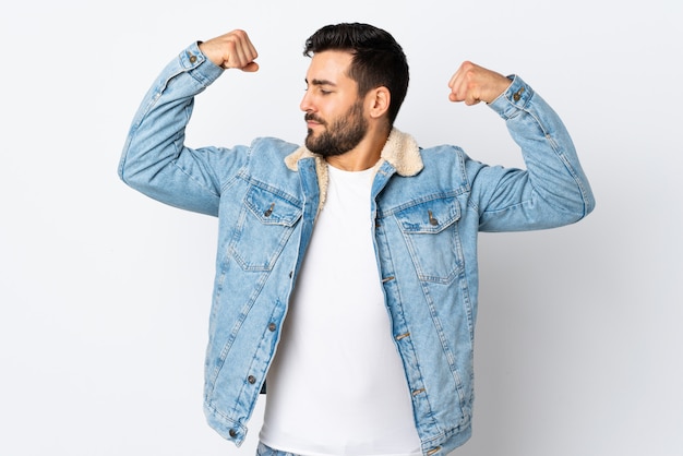 Joven guapo con barba aislado en la pared blanca haciendo un gesto fuerte